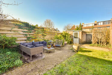 Terrace of residential building with comfortable sofa and grassy lawn with green trees growing on summer day in suburb area - ADSF41468