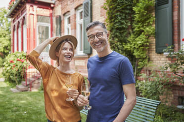 Happy man and woman holding wineglasses in garden - RORF03145