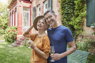 Happy mature man and woman holding wineglasses in back yard - RORF03146