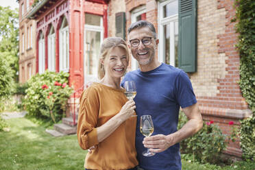 Happy couple holding wineglasses in garden - RORF03147