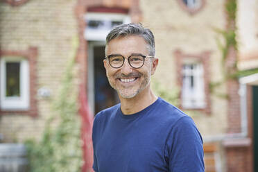 Lächelnder Mann mit Brille vor einem Haus - RORF03171