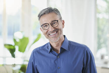 Happy man wearing eyeglasses at home - RORF03224