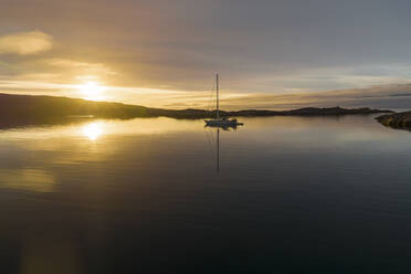 Luftaufnahme eines Segelboots in einer Bucht bei Sonnenuntergang an der Küste, Sermersooq, Grönland. - AAEF17053