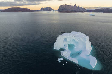 Luftaufnahme einer großen Eisformation entlang der Küste in einem Fjord bei Sonnenuntergang, Sermersooq, Grönland. - AAEF17067