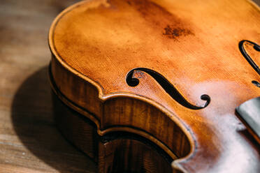 High angle piece of wooden shiny polished violin placed on table in luthier workshop - ADSF41501