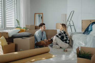 Ein fröhliches junges Paar in seiner neuen Wohnung, das den Umzug plant. - HPIF00937