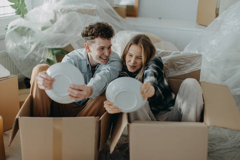 A cheerful young couple in their new apartment, having fun when unpacking. Conception of moving. - HPIF00942