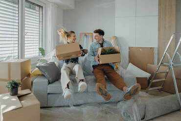 A cheerful young couple in their new apartment, carrying boxes. Conception of moving. - HPIF00943