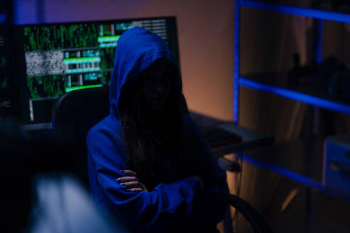 Ein vermummter anonymer Hacker am Computer in einem dunklen Raum bei Nacht, Cyberwar-Konzept. - HPIF00992