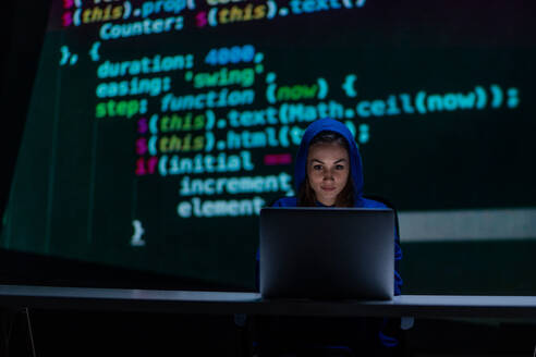 Eine vermummte anonyme Hackerfrau am Computer in einem dunklen Raum bei Nacht, Cyberwar-Konzept. - HPIF00998