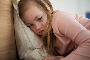 Ein trauriges kleines Mädchen mit Down-Syndrom liegt zu Hause im Bett. - HPIF01015