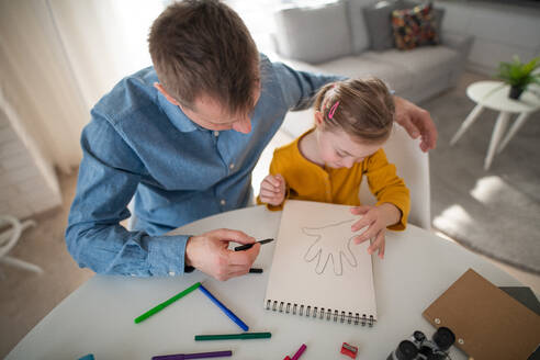 Ein Vater mit seiner kleinen Tochter mit Down-Syndrom beim Lernen zu Hause. - HPIF01051