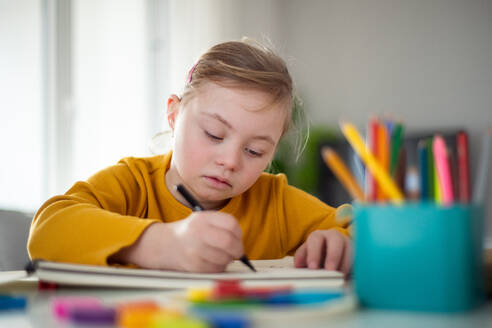 A little girl with Down syndrome drawing at home. - HPIF01056