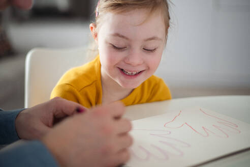 A father with his little daughter with Down syndrome drawing at home. - HPIF01058