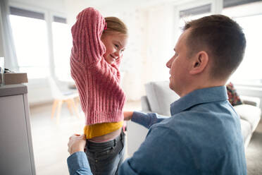 Ein Vater zieht seiner kleinen Tochter mit Down-Syndrom verschiedene Socken an, wenn sie zu Hause im Bett sitzt. - HPIF01061