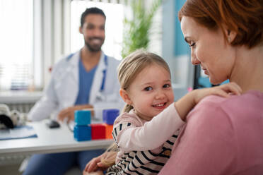 A little girl with her mother at doctor's office on consultation, looking at camera. - HPIF01146