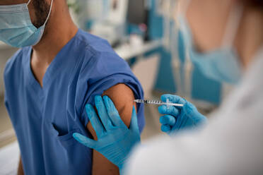 A close-up of doctor getting covid-19 vaccince from his colleague. - HPIF01159