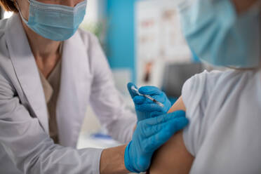 A close-up of young man getting covid-19 vaccince from his doctor in clinic. - HPIF01163