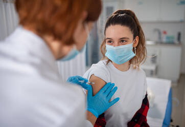 A young woman getting covid-19 vaccince from doctor in clinic. - HPIF01164