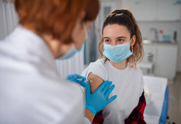 Eine junge Frau wird vom Arzt in der Klinik gegen Covid-19 geimpft. - HPIF01164