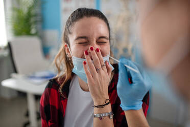 A doctor taking nasal swab test from young woman in clinic. - HPIF01165