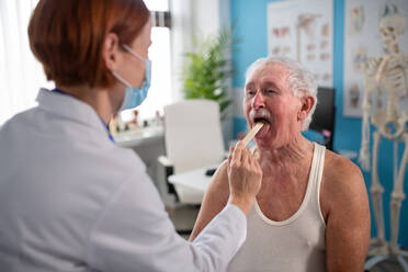 A female doctor checking senior's man throat in her office. - HPIF01176