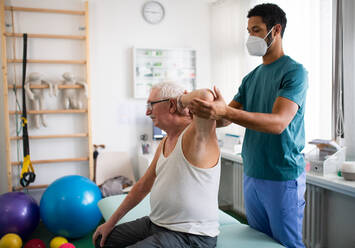 Eine junge Physiotherapeutin übt mit einem älteren Patienten in einem Behandlungsraum. - HPIF01183