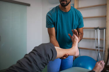 A close-up of physiotherapist exercising with senior patient's leg in a physic room. - HPIF01193