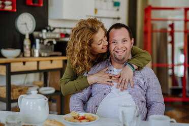 A portrait of happy man with Down syndrome with his mother at home having breakfast together. - HPIF01209