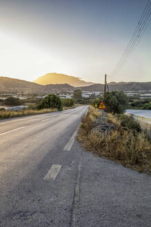 Griechenland, Kreta, Agia Galini, Leere Landstraße bei Sonnenuntergang - MAMF02319