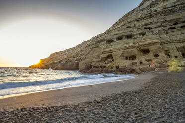 Greece, Crete, Matala, Matala Beach and cliffside caves at sunset - MAMF02322