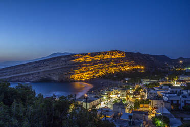 Greece, Crete, Matala, View of illuminated coastal village at night - MAMF02326