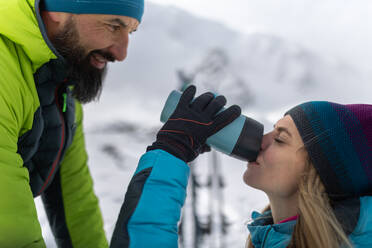 Ein Skitourenpaar macht Pause und trinkt Tee aus einer Thermoskanne, während es einen Berg in der Niederen Tatra in der Slowakei besteigt. - HPIF01224