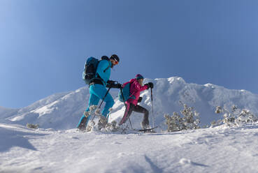 Ein Skitourenpaar beim Wandern in den Bergen aus einem niedrigen Blickwinkel. - HPIF01230