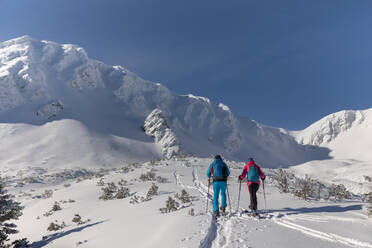 A ski touring couple hiking up a mountain in the Low Tatras in Slovakia. - HPIF01231