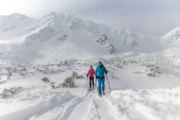 A female backcountry skier hiking to the summit of a snowy peak in the Low Tatras in Slovakia. - HPIF01236