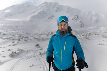 Ein männlicher Skitourengeher auf dem Weg zum Gipfel eines verschneiten Berges in den Schweizer Alpen - HPIF01237