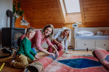 Ein Junge mit Down-Syndrom, dessen Mutter und Großmutter zu Hause den Teppich aufrollen. - HPIF01265