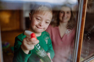Ein Junge mit Down-Syndrom und seine Mutter beim Fensterputzen zu Hause. - HPIF01268