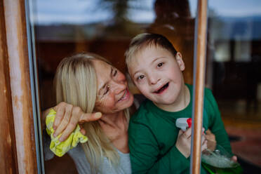 Ein Junge mit Down-Syndrom mit seiner Mutter und Großmutter beim Fensterputzen zu Hause. - HPIF01270