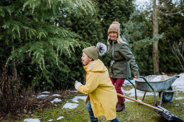 Ein Junge mit Down-Syndrom und seine Großmutter arbeiten im Winter gemeinsam im Garten. - HPIF01283