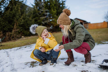 Ein Junge mit Down-Syndrom und seine Mutter spielen mit Schnee im Garten. - HPIF01284