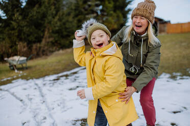 Ein Junge mit Down-Syndrom und seine Mutter spielen mit Schnee im Garten. - HPIF01285