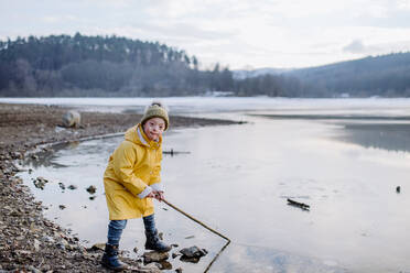 Ein glücklicher kleiner Junge mit Down-Syndrom schaut im Winter draußen am See in die Kamera. - HPIF01293