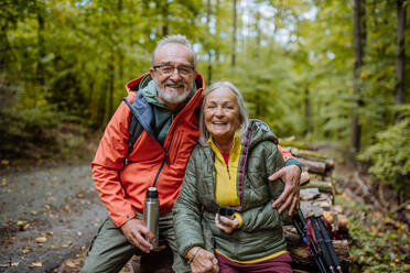 Ein älteres Ehepaar macht eine Pause beim Wandern im Herbstwald. - HPIF01300