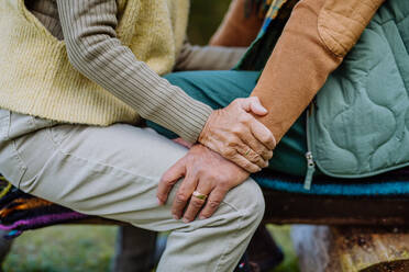 Mittelteil eines älteren Paares, das auf einer Bank sitzt und sich gegenseitig umarmt. - HPIF01338