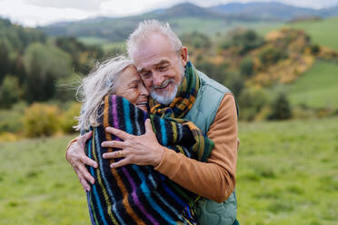 Verliebtes älteres Paar umarmt sich im Herbstwald. - HPIF01346