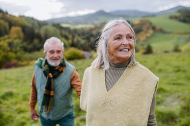 Portrait of happy senior couple walking in autumn nature. - HPIF01349