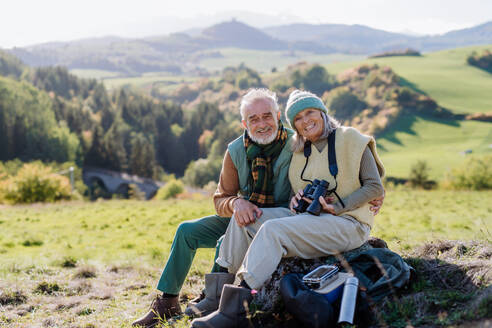Älteres Paar, das eine Pause einlegt und beim Wandern in der herbstlichen Natur sitzt. - HPIF01361
