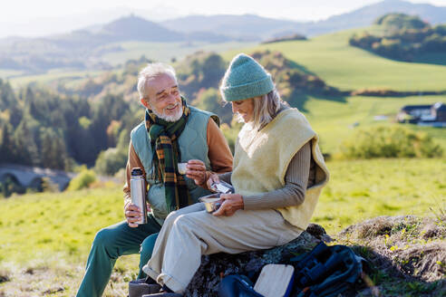 Senior couple having a break during hiking in autumn nature. - HPIF01362
